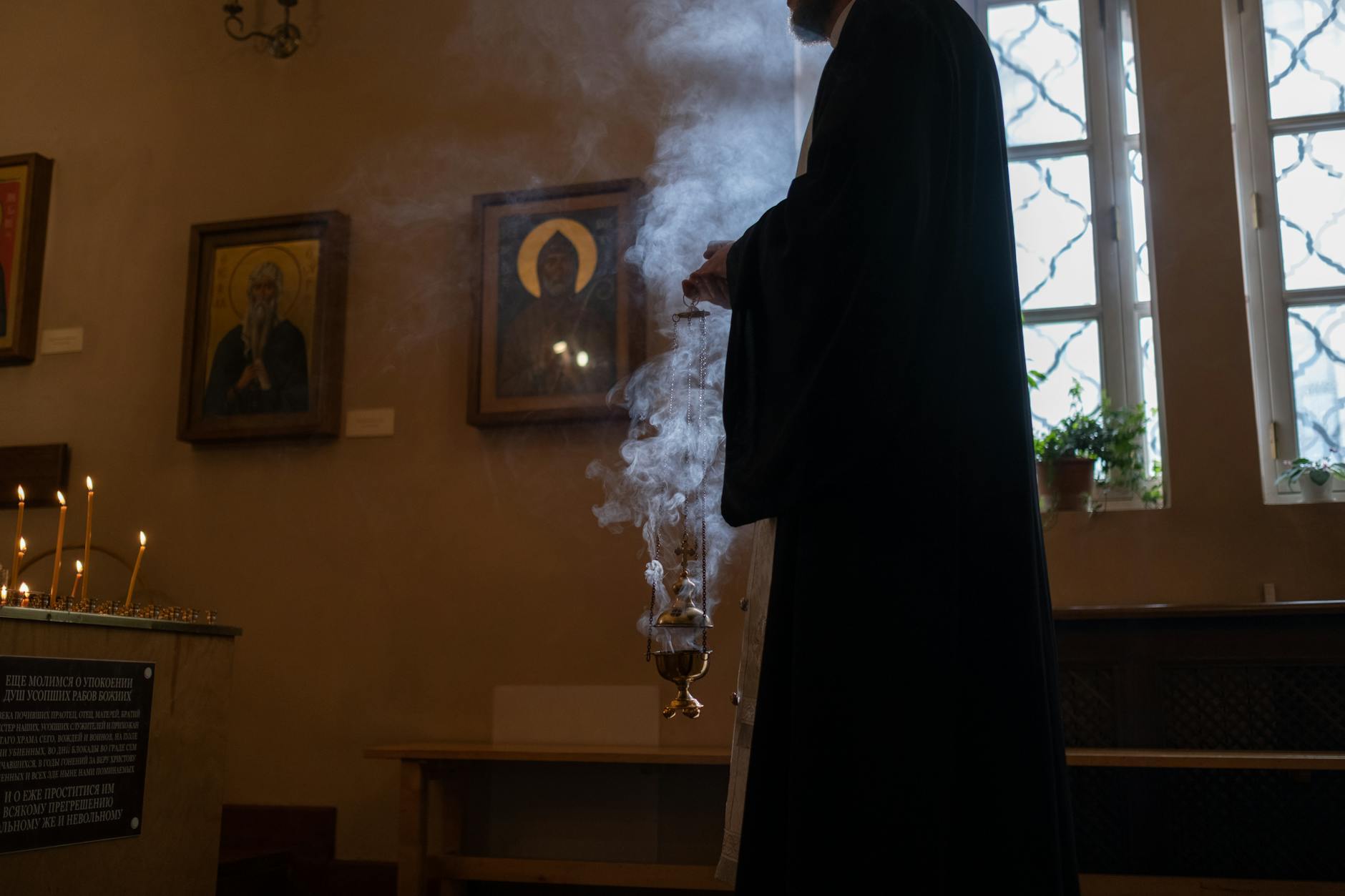 an elderly priest in a quiet church corner surrounded by religious artifacts
