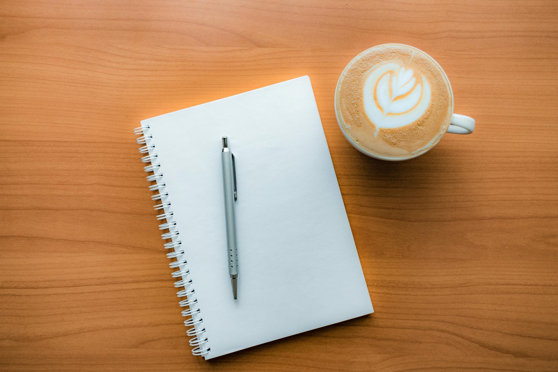 journal and pen with coffee on a table